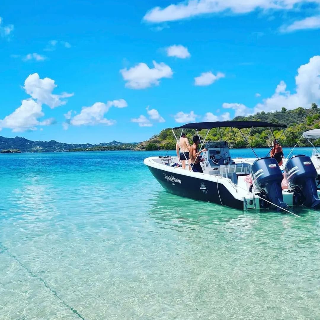 The Rum N'Fishing boat anchored in turquoise water, ready for an inter-island transfer